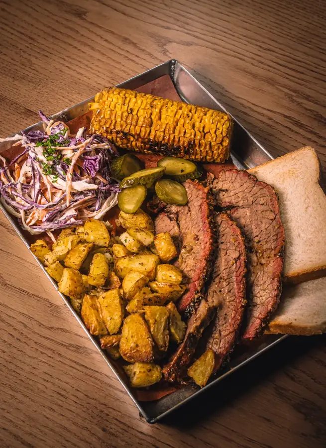 Vassoio texano con brisket a fette, patate, coleslaw e pannocchia